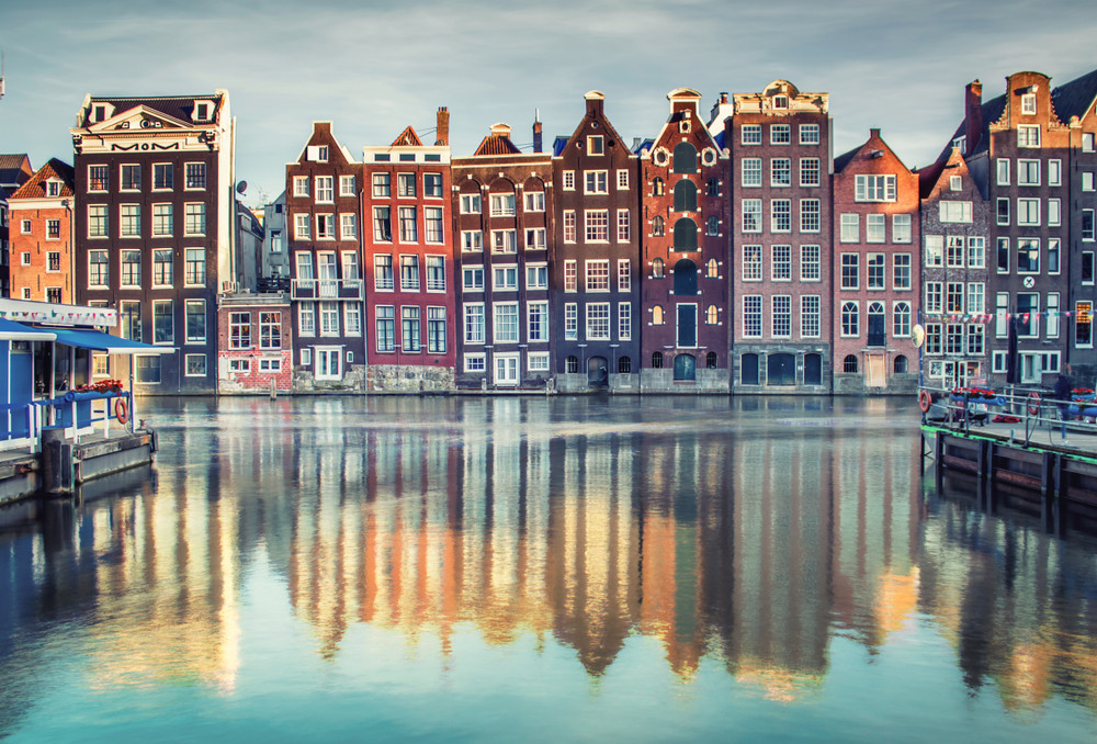 Colorful houses lining a canal in Amsterdam under a blue sky