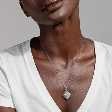 A square sterling silver floral locket, highlighting its unique shape and floral design, suggesting photos that complement the square frame