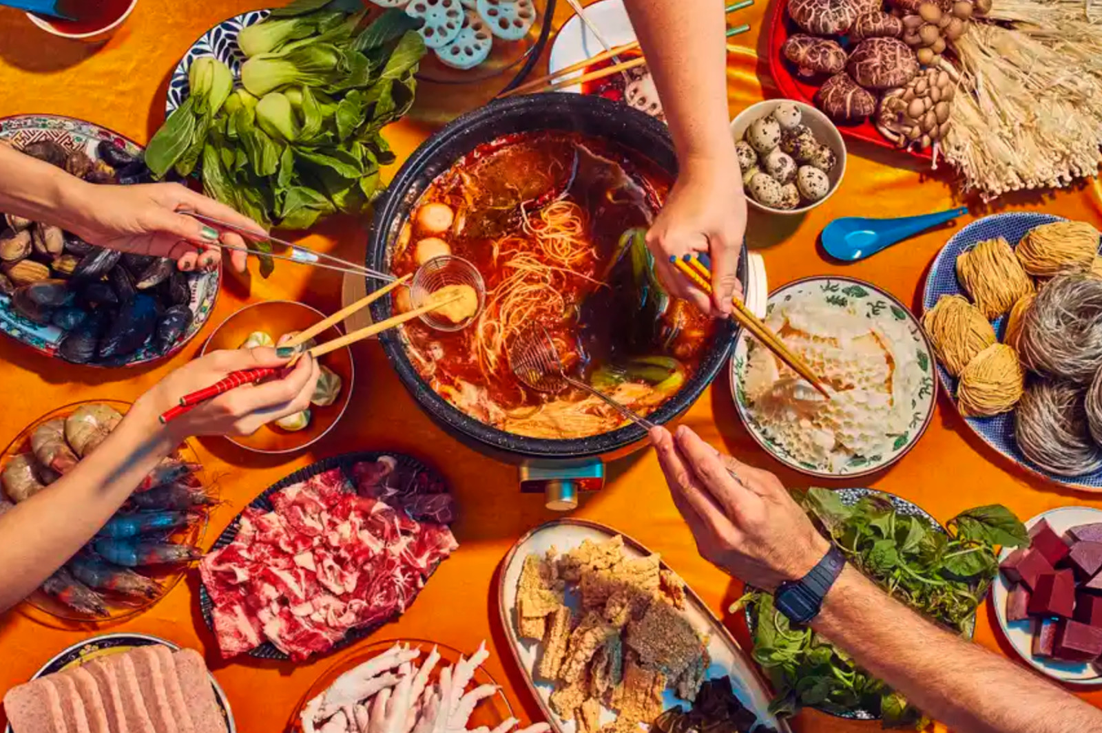 Fly by Jing's overhead shot of a hot pot spread, taken with a stabilized camera, showcases the vibrant colors and textures of all the ingredients.