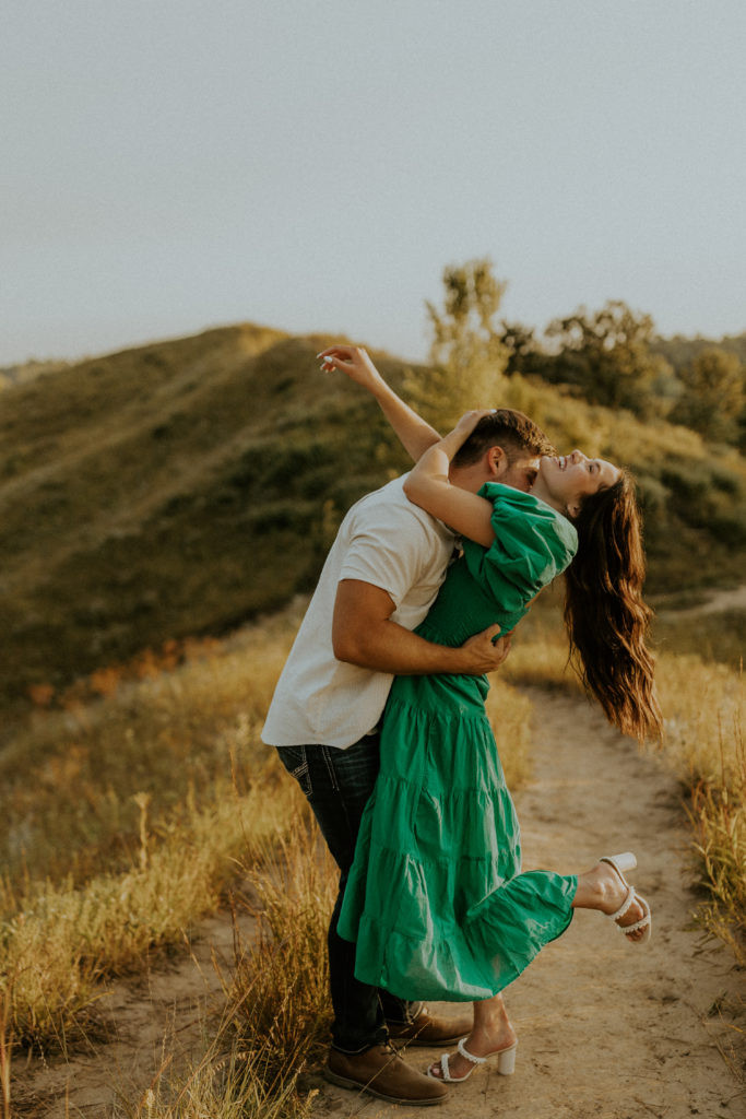 Engagement photo of a couple embracing, with the woman in a burgundy dress, demonstrating how color can add richness to engagement photos.