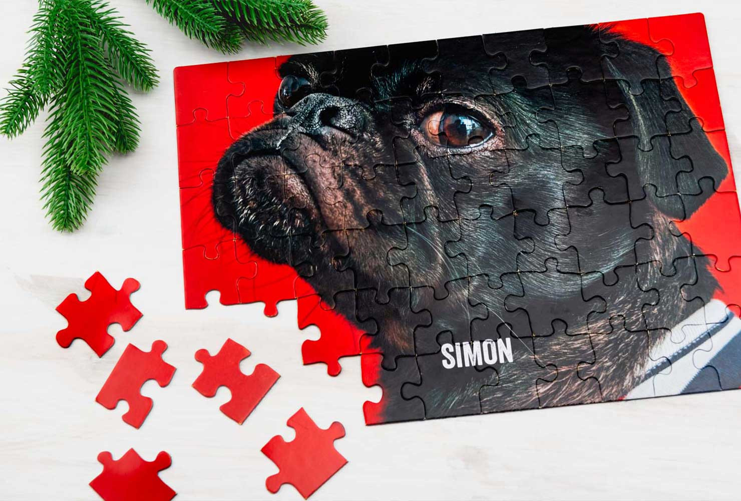 A man sits at a table, diligently piecing together a custom jigsaw puzzle that features a photograph of his beloved pet dog.