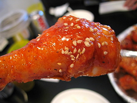 A close-up of spicy chicken wing from CheoGaJip, showcasing the heavy sauce glazing
