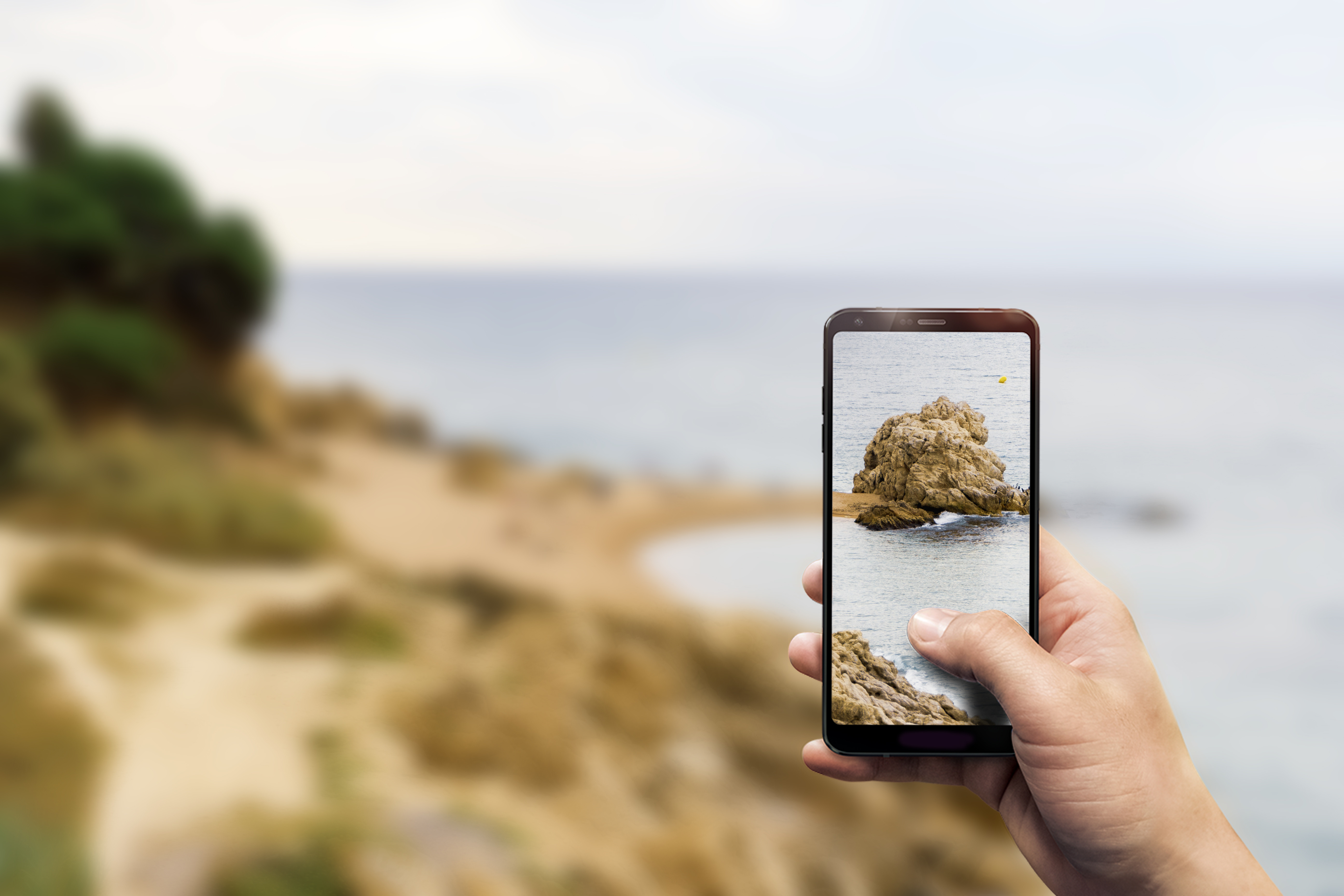 Photograph of a person taking a photo of the ocean with their smartphone