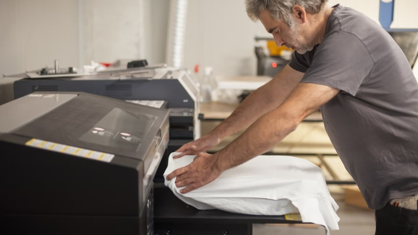 Close-up of a direct-to-garment printer applying ink to a white t-shirt, showcasing the detailed print quality achievable with DTG printing