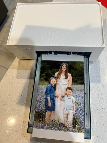 Photo printer sitting on a desk next to creatively displayed printed photos, illustrating creative photo displays