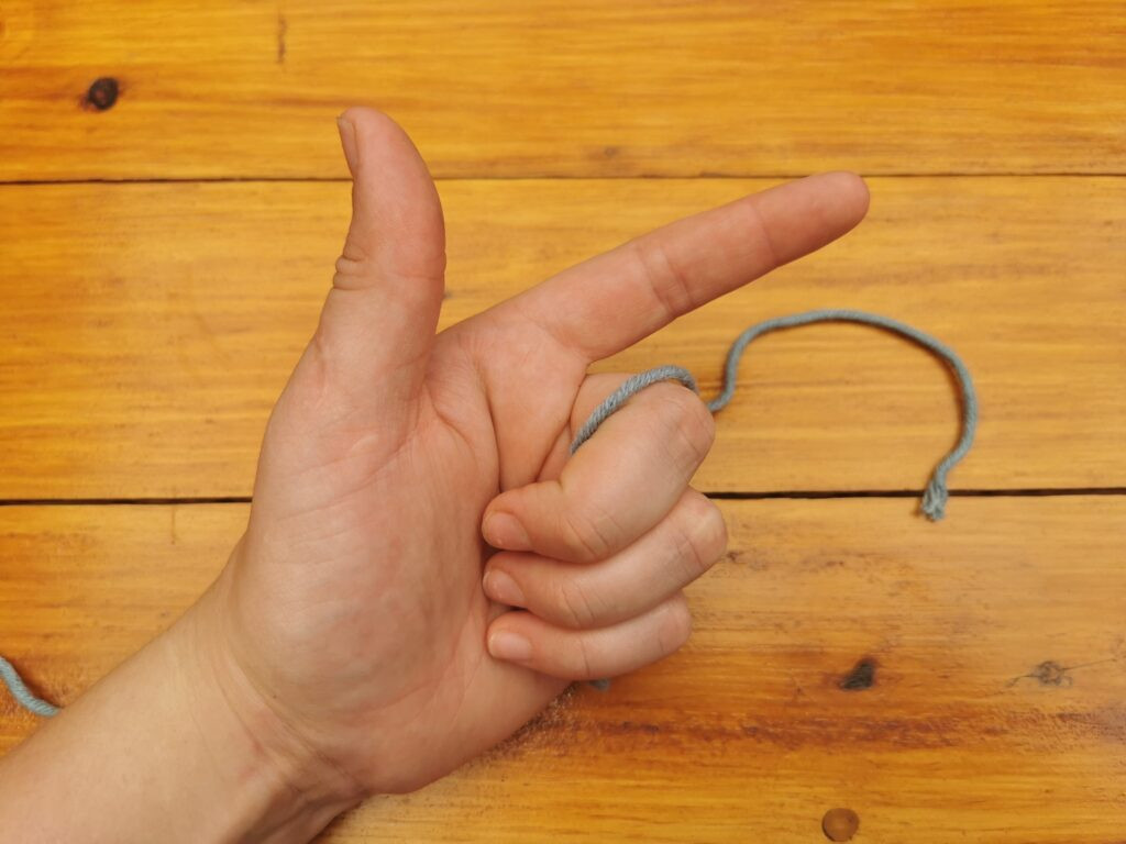 Grabbing the yarn with three fingers prepares to form the initial loop for crocheting photos