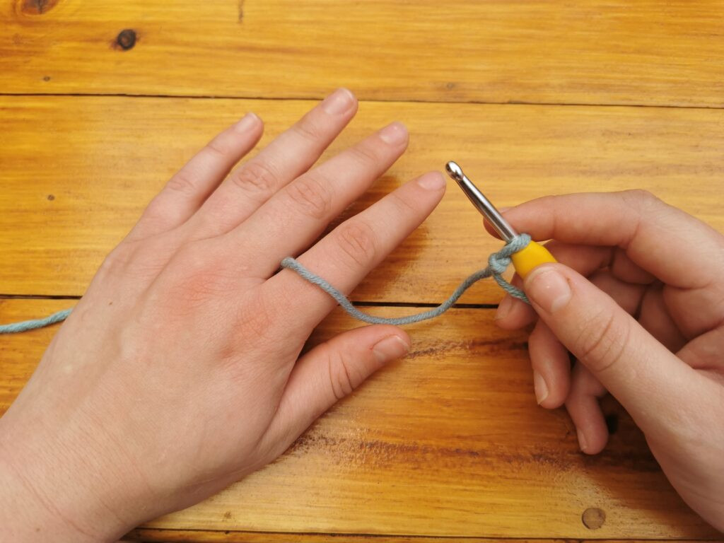 Positioning the yarn between the fingers stabilizes it, aiding in consistent tension control