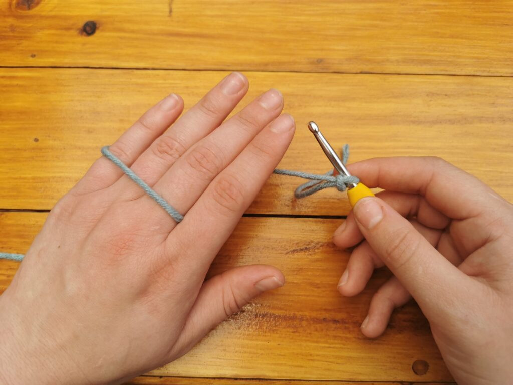 Wrapping the yarn around the pinky and index finger helps maintain even tension during crocheting