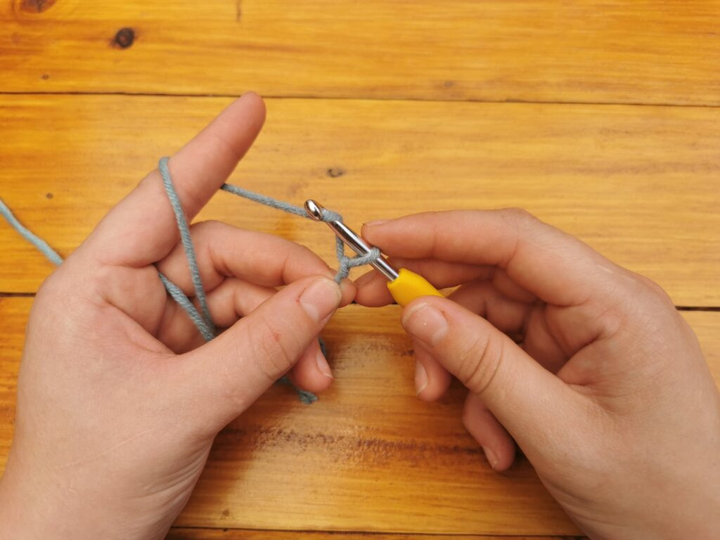 Bringing the yarn over the hook prepares to pull through, forming the chain stitch