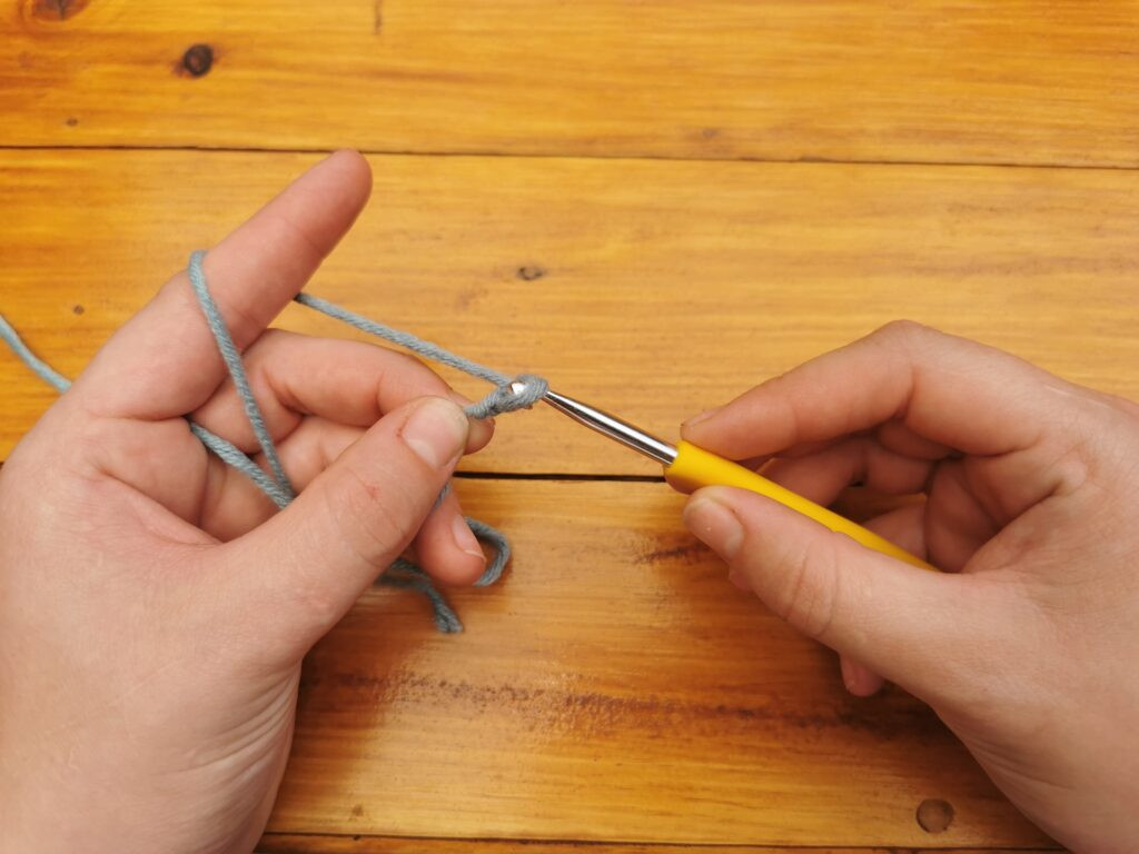 Pulling the yarn through the loop creates the first chain of the crochet foundation