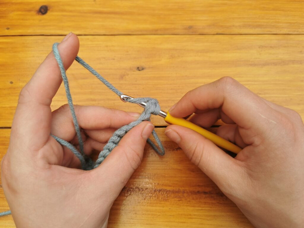 Yarning over the hook prepares to pull through, initiating the single crochet stitch