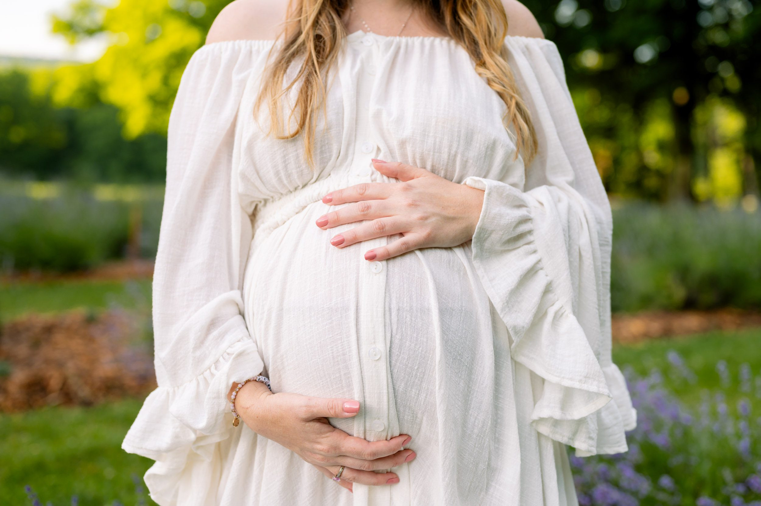 Close-up of expecting mother in lavender field, captured at 28 weeks