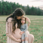 Pregnant mother in white dress standing in a field