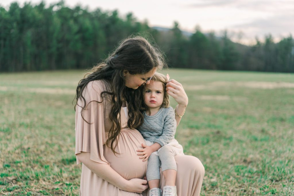 Pregnant mother in white dress standing in a field