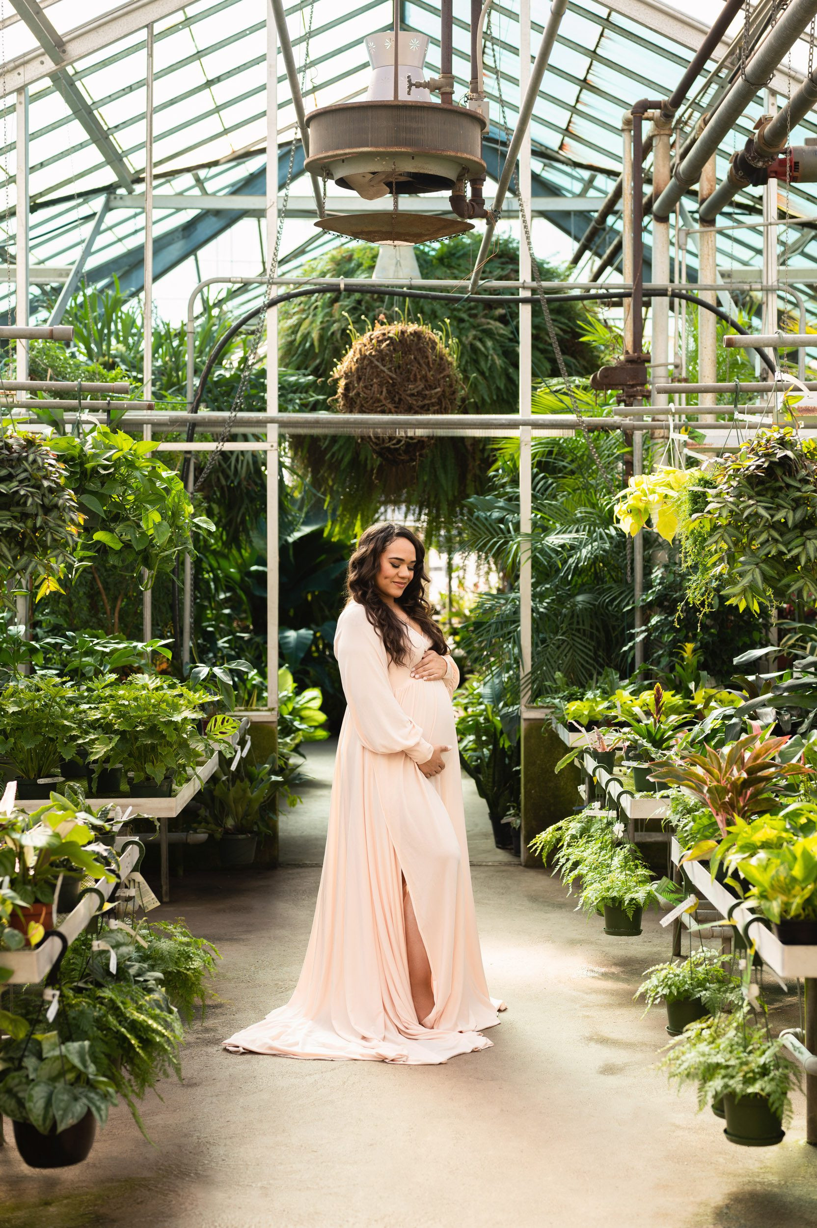 Expecting mom in pink dress in greenhouse, captured at 30 weeks