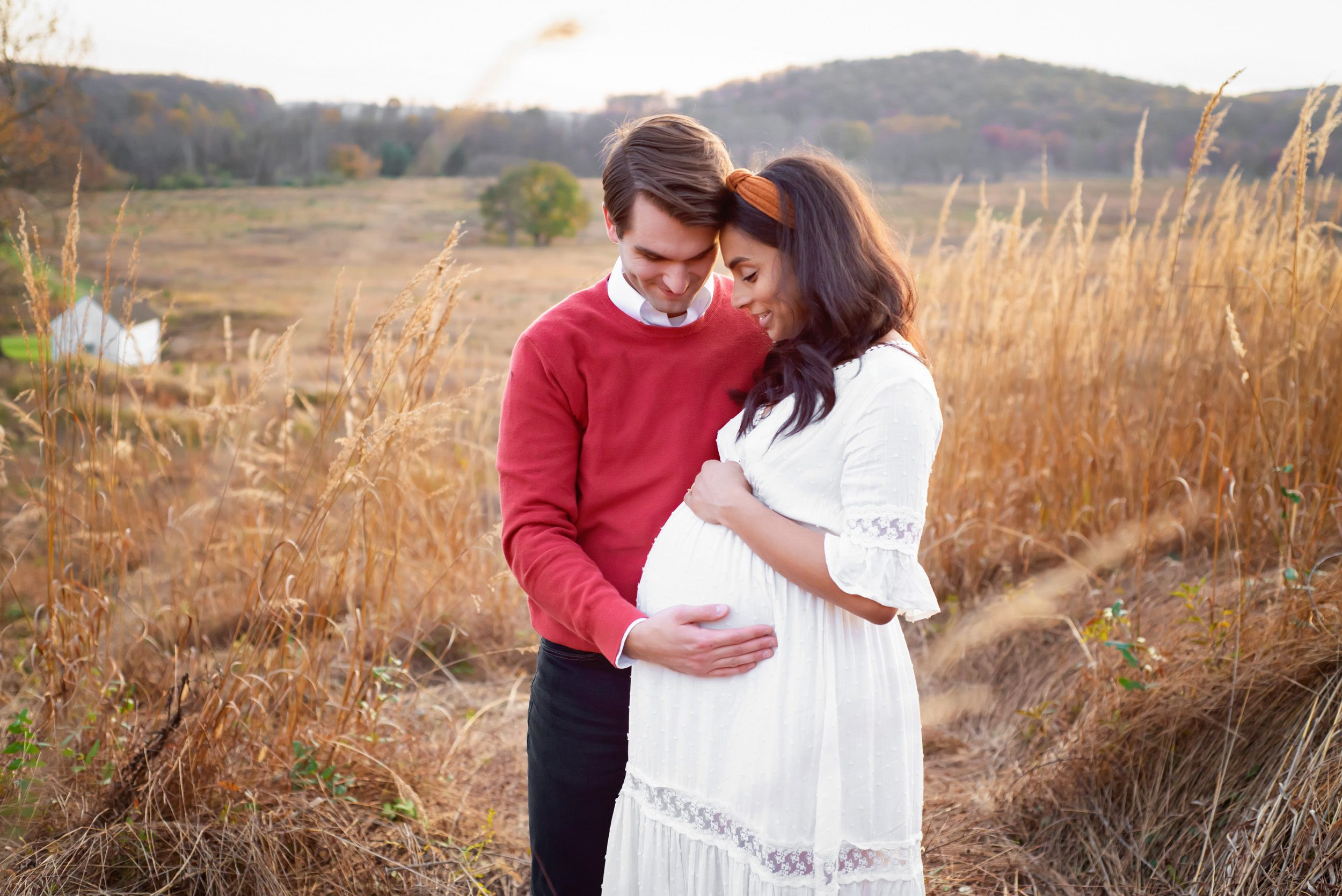 Expecting couple in golden field, captured at 34 weeks