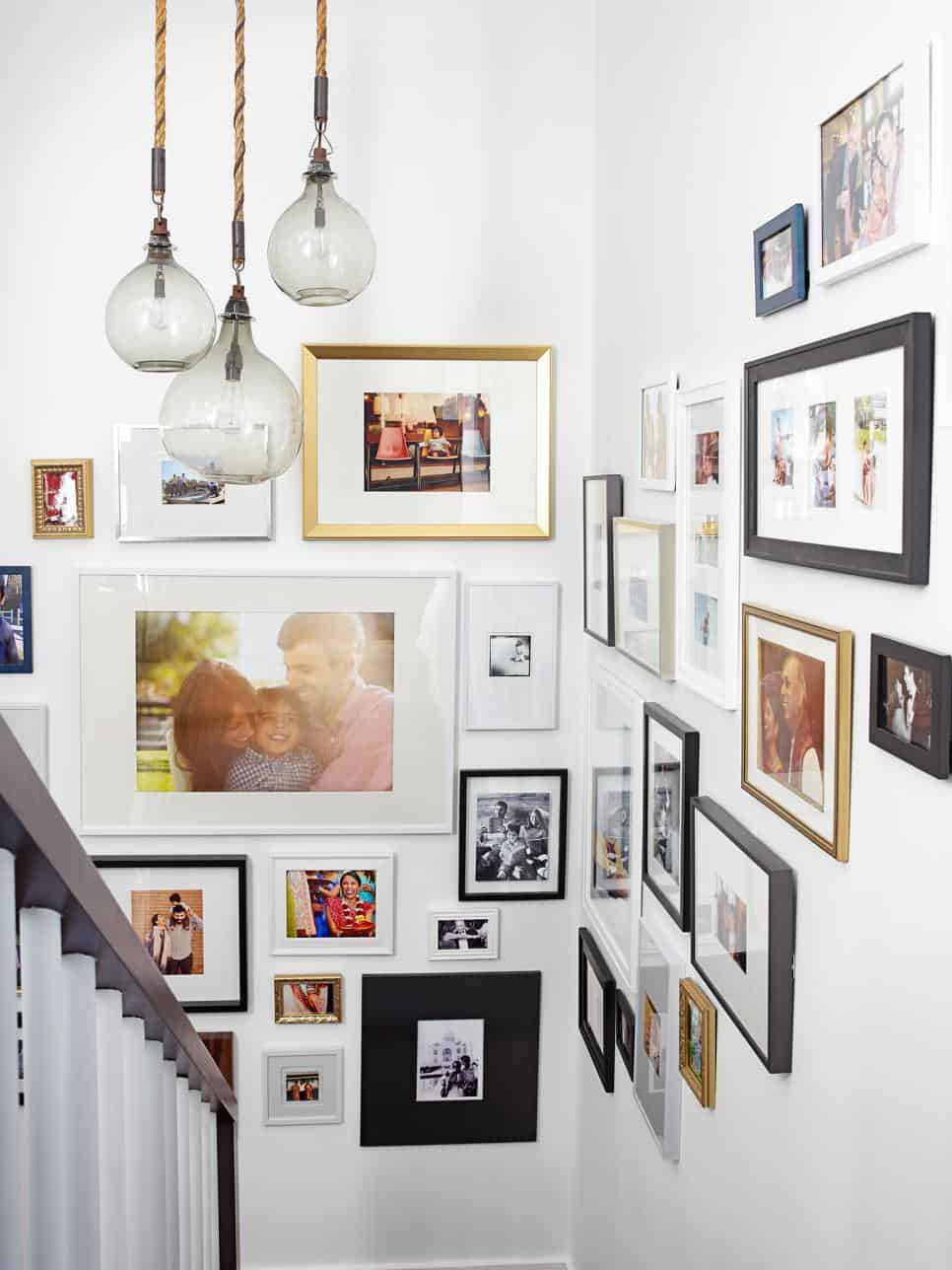 Eclectic family photo gallery wall using a mix of frames, sizes, and styles on a stairwell.