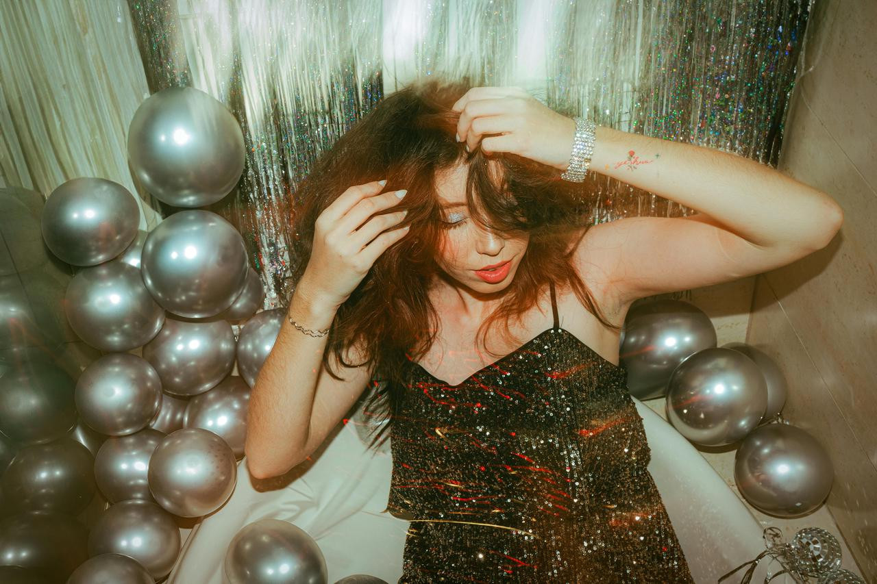 A girl poses in front of the silver balloon disco backdrop.