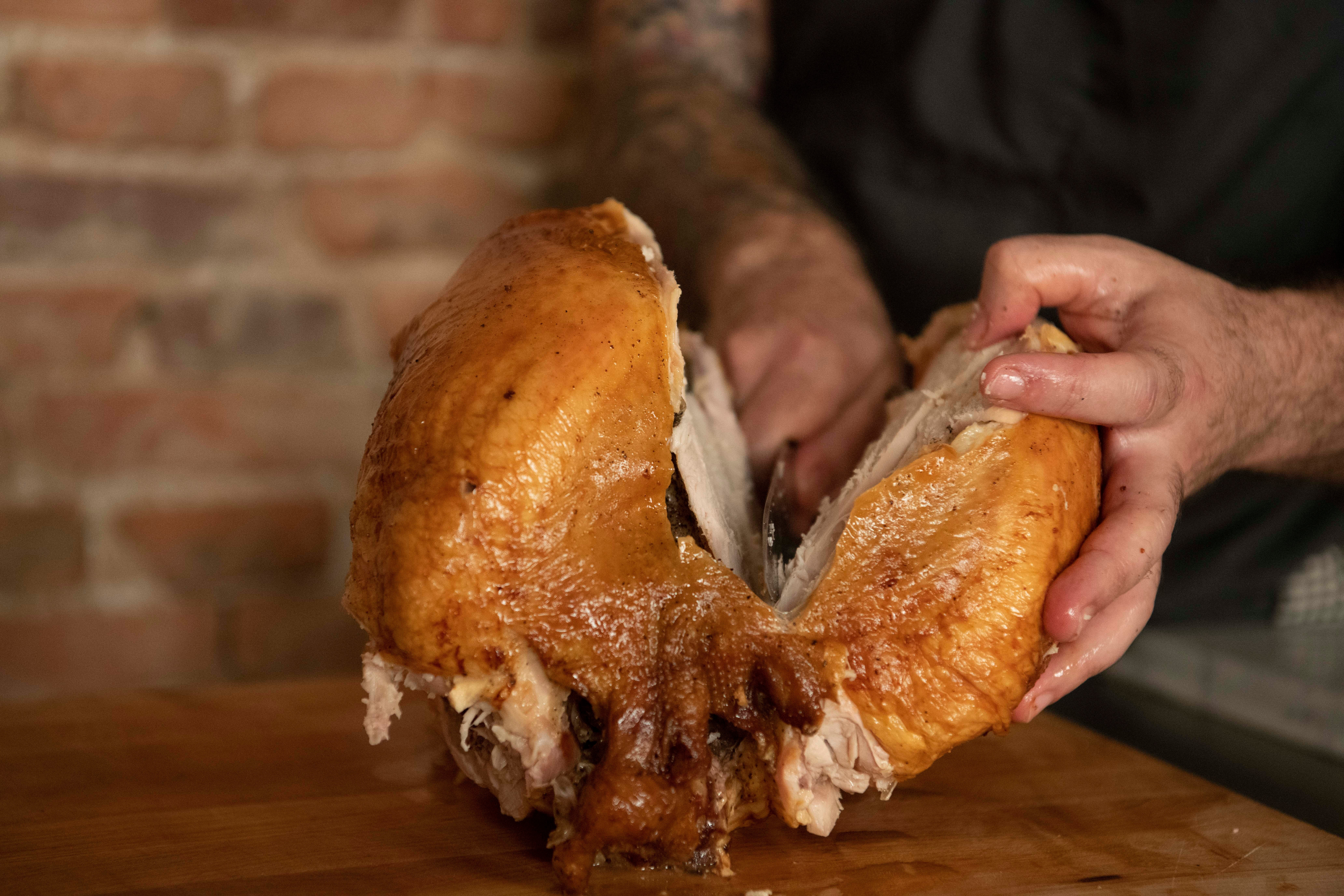 Removing the breast meat of a roasted turkey by slicing along the breastbone with a carving knife