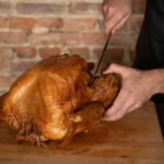 Removing the turkey leg by cutting through the joint with a sharp knife