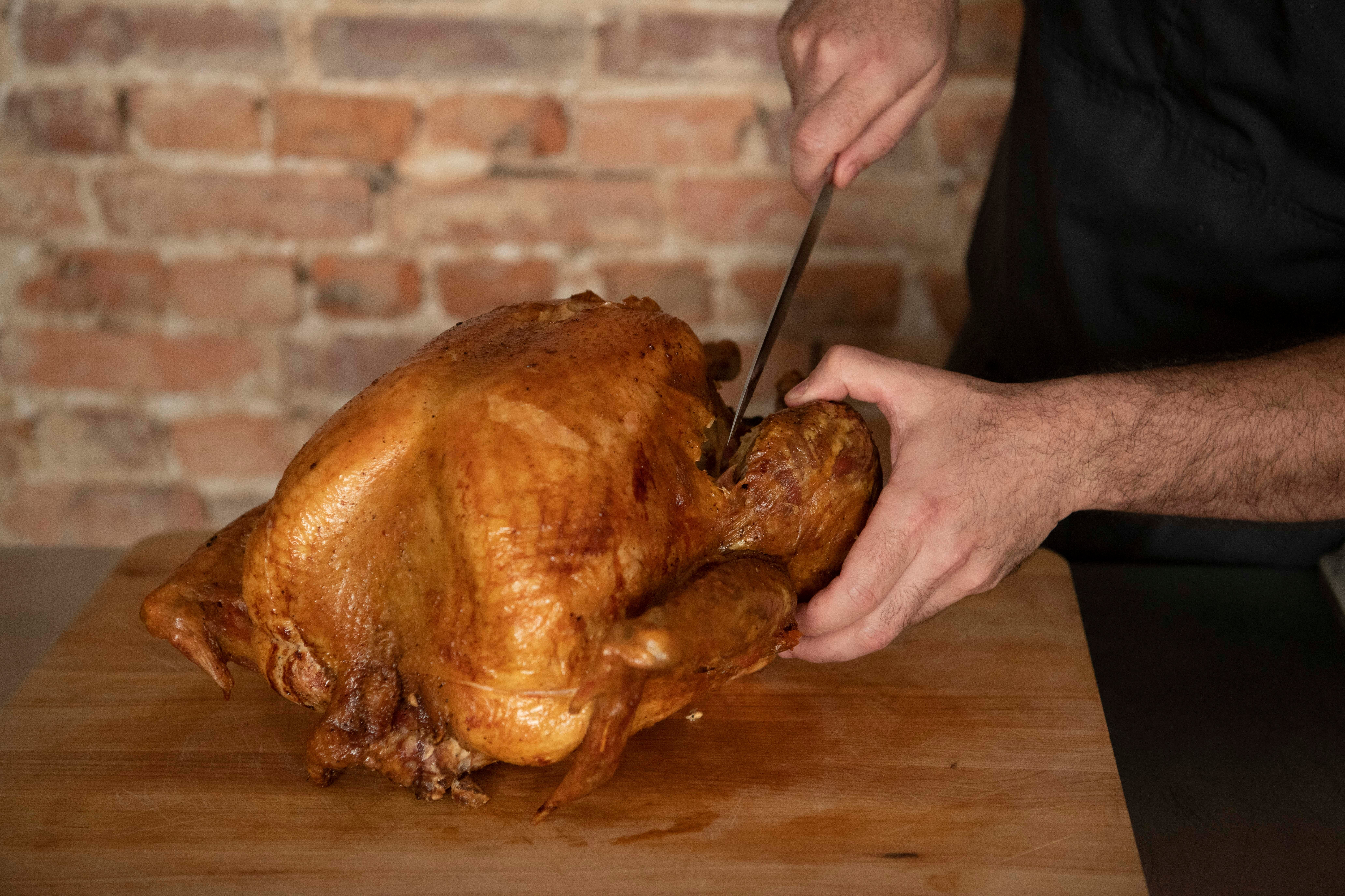 Removing the turkey leg by cutting through the joint with a sharp knife
