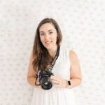 Family photographer Kelley Hoagland holds camera and smiles.