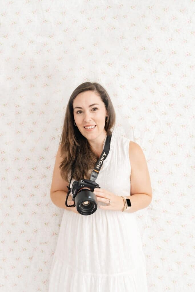 Family photographer Kelley Hoagland holds camera and smiles.