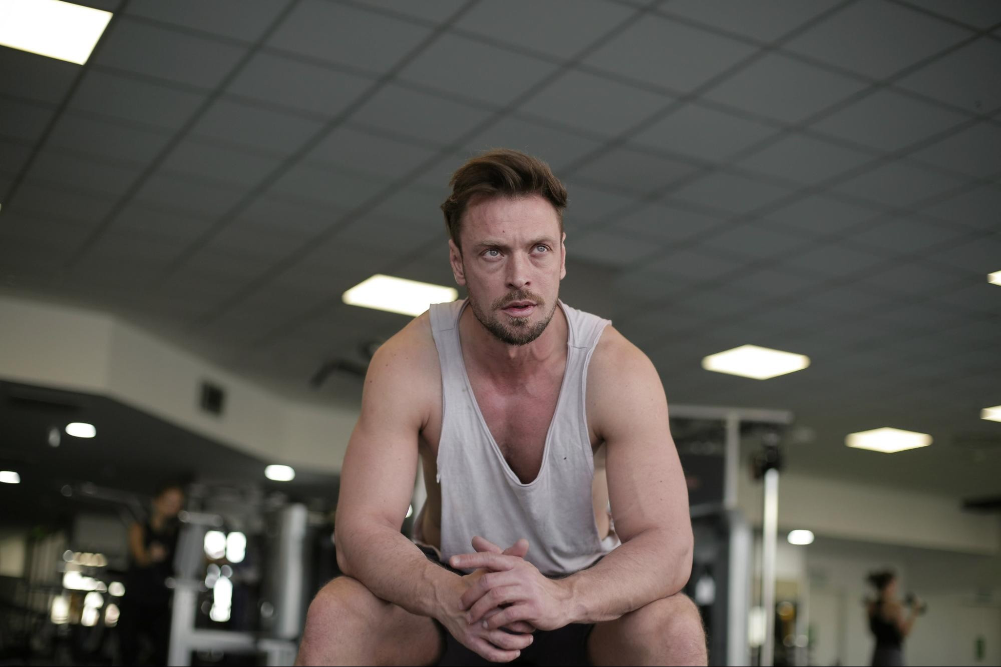 Male athlete seated in gym with corrected skin tones for a more natural appearance; before and after comparison.