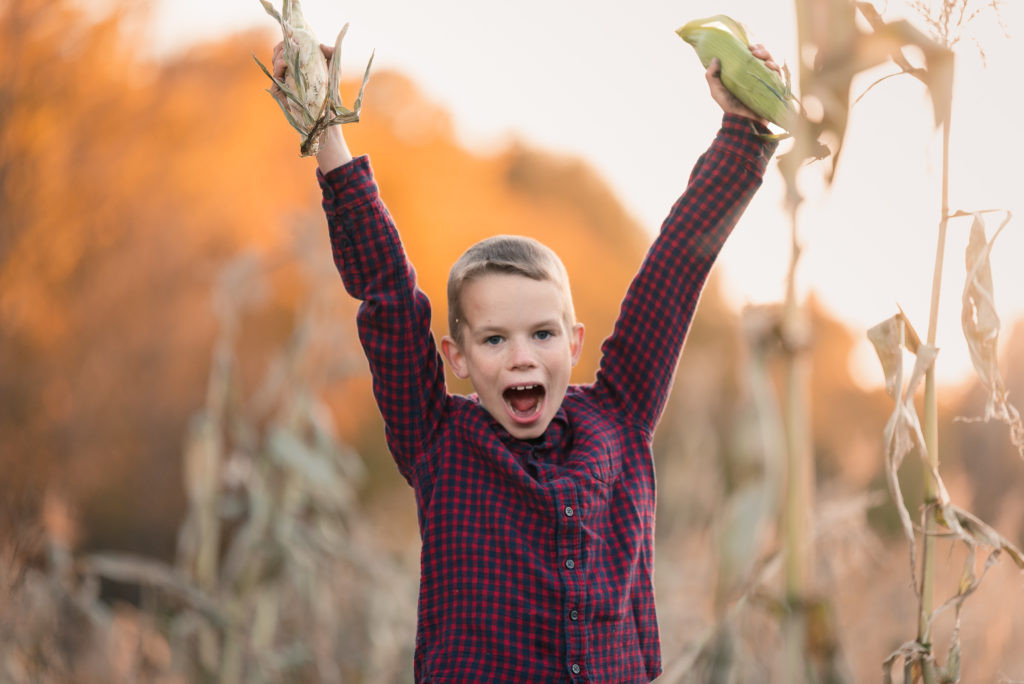 Child holding corn on a farm.