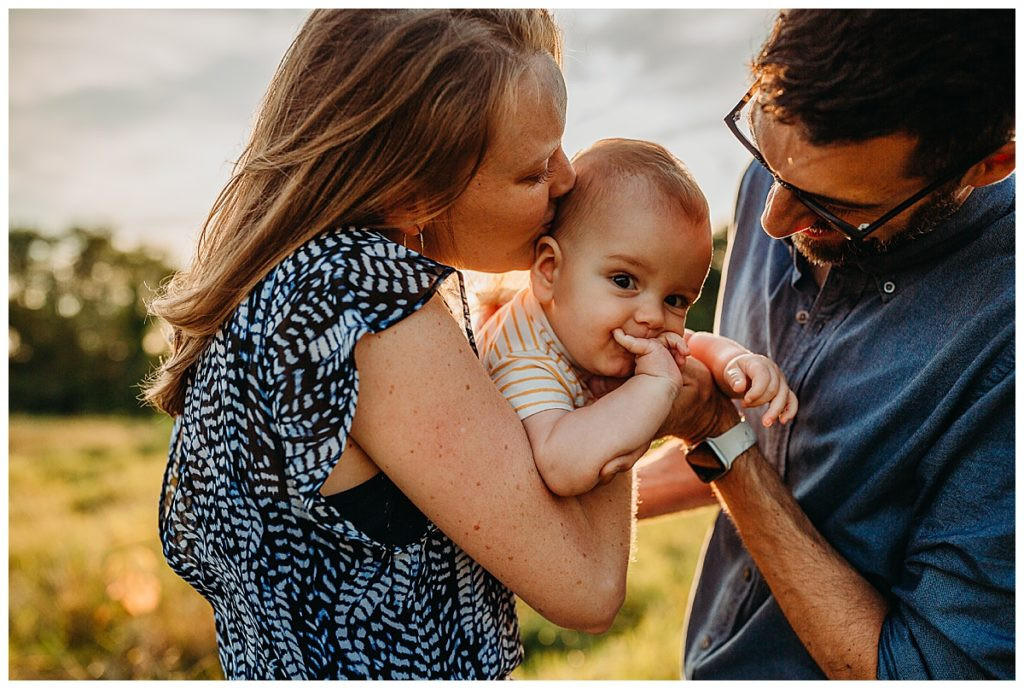 Mom and Dad Snuggle Baby Boy During Outdoor Pictures