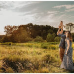 Family Lifts Child in the Air at Sunset in a Field during Photoshoot