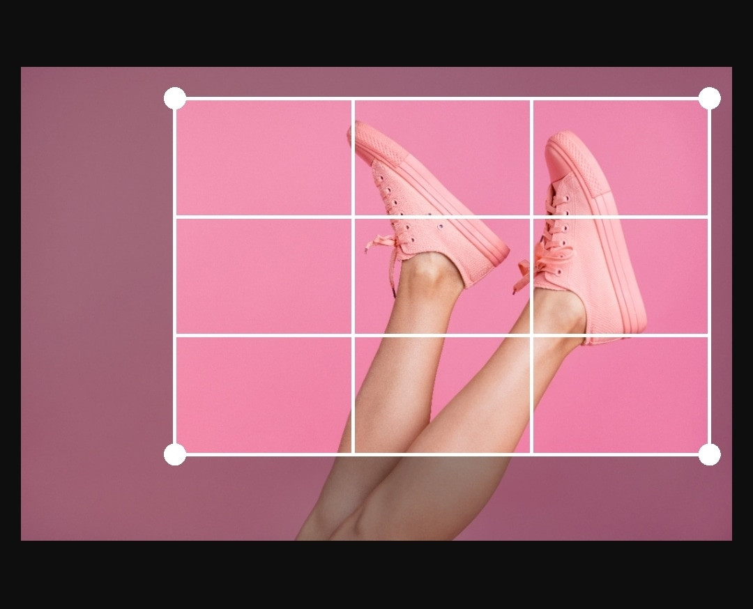 Pink sneakers on pink background with cropping grid overlay for adjustment.