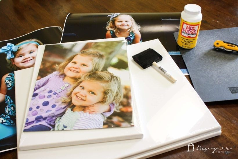 Materials for DIY photo canvas including canvas, photo print, Mod Podge, foam brushes, acrylic paint, and Exacto knife