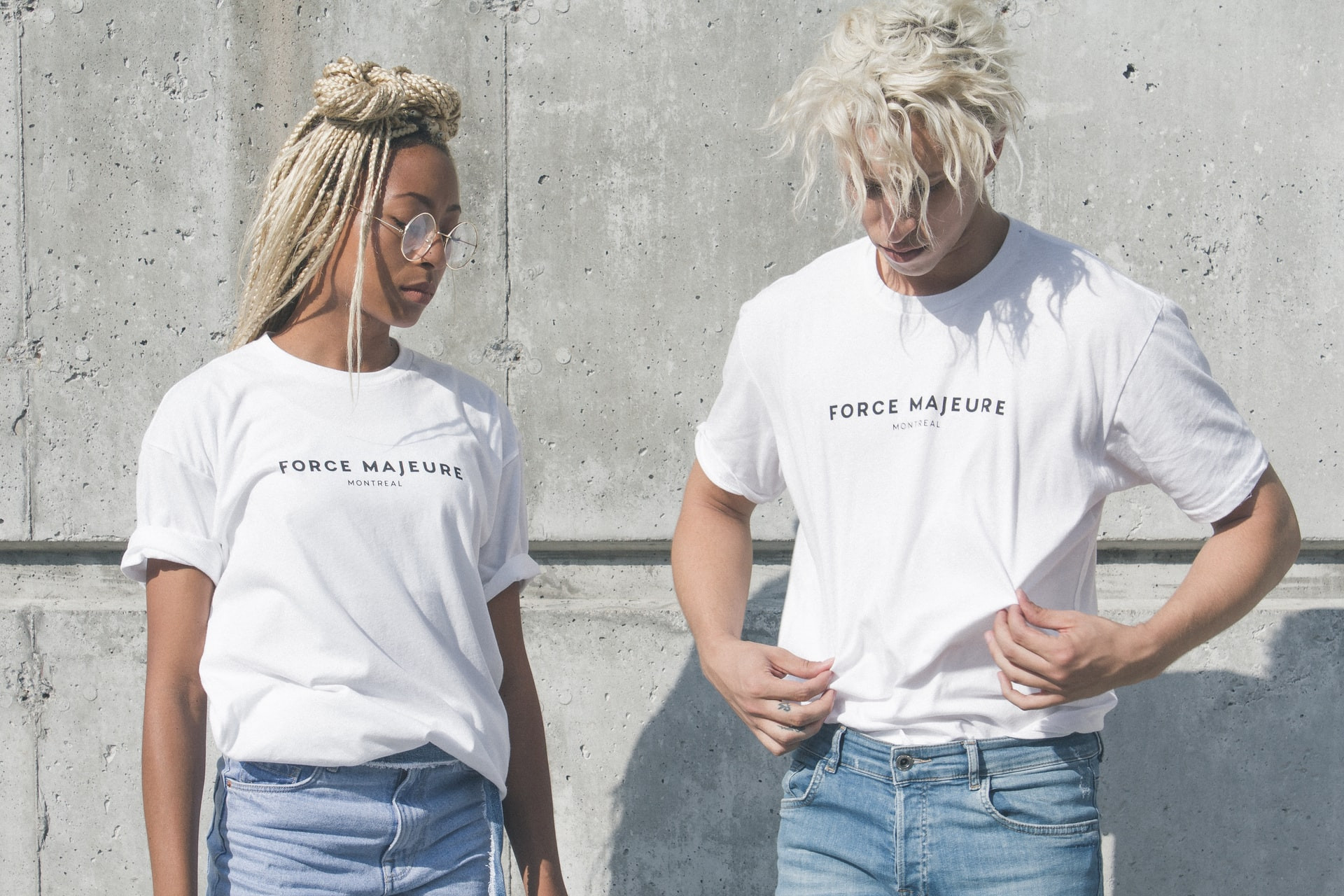 Woman and man showcasing their t shirts, both smiling and presenting the garments