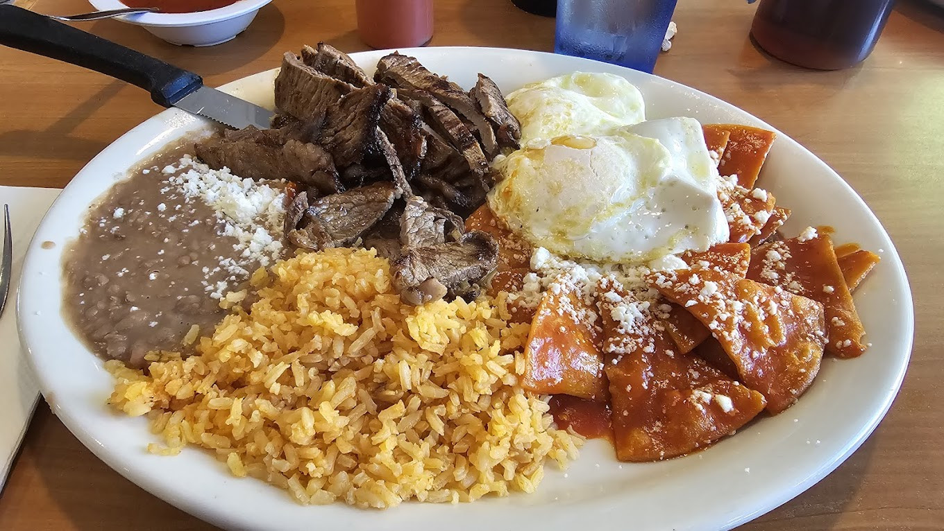 Chilaquiles rojos, with mexican rice, beans with cheese, grilled steak and two sunny side up eggs.