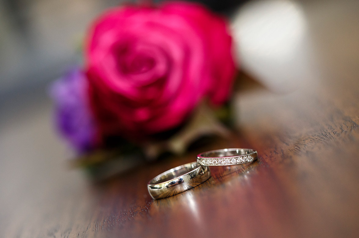 Wedding couple smiling at each other with their wedding bands shining
