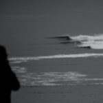 Black and white photo using the rule of thirds, showing a silhouette against a crashing wave