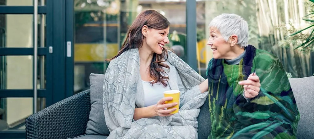Young woman enjoying her morning coffee wrapped in a plush photo blanket, exemplifying comfort and cherished memories.