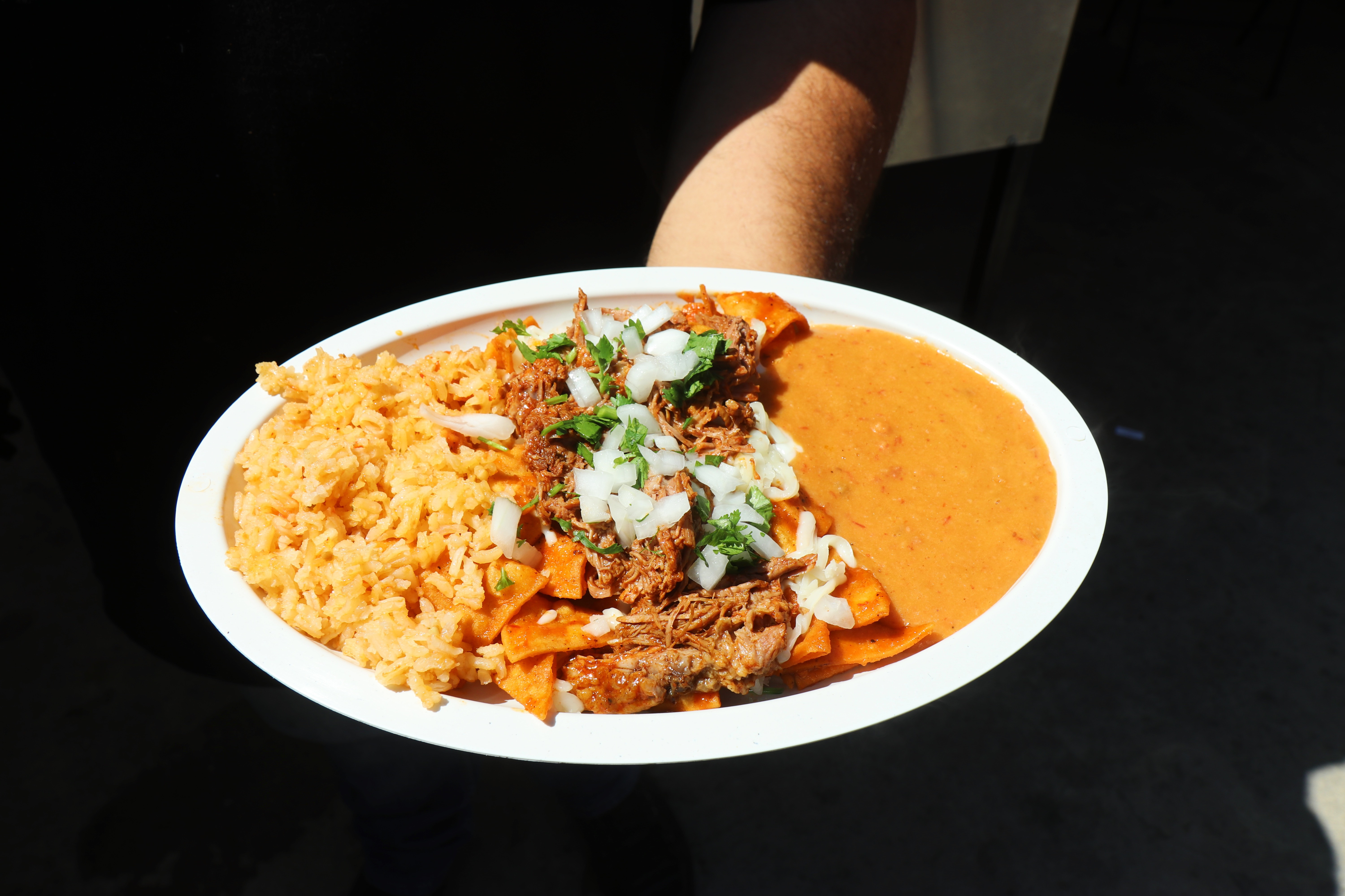 Birriaquiles plate complete with homemade red chilaquiles topped with birria and served with rice and charro beans.