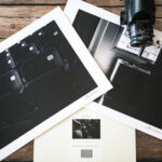 Flat lay of black and white lustre print photographs and a camera on a table