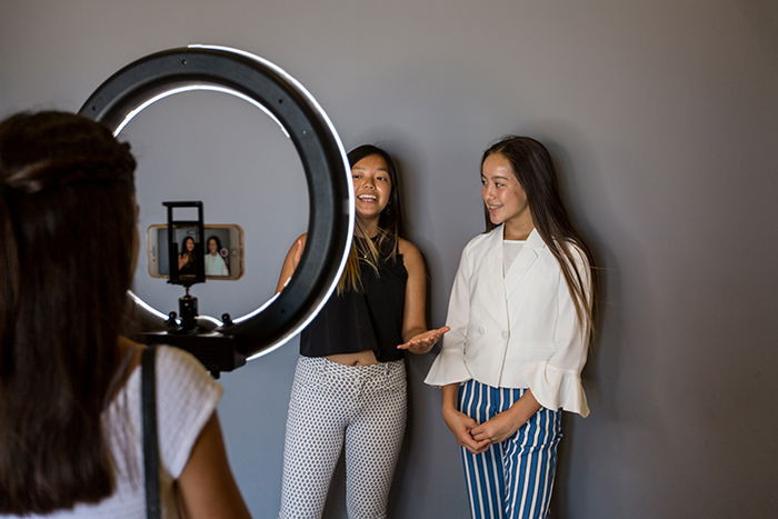 Two female models being photographed in a freelance photographer home studio space, highlighting the dynamic environment of a professional photoshoot
