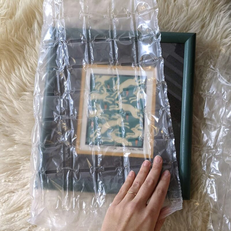 Hands carefully folding the end flaps of wrapping paper