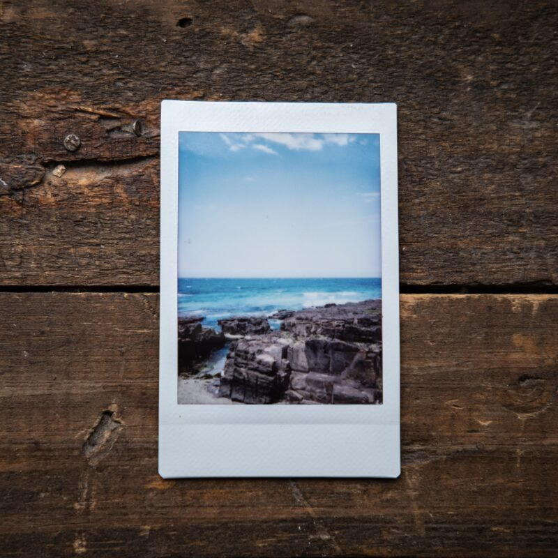 Close-up shot of a person's hands carefully inserting a Polaroid photo into a frame, highlighting the precision needed to preserve the white border.