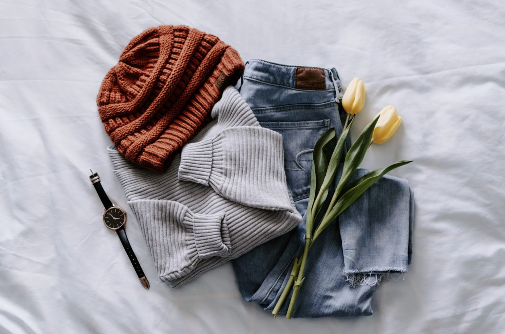 Flatlay disposition of clothes showcases various clothing items arranged on a clean backdrop