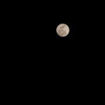 A detailed close-up of the moon's surface, showing craters and textures, captured with a telephoto lens, demonstrating manual focus and optimal settings for lunar photography.