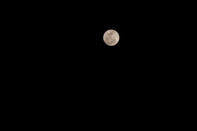 A detailed close-up of the moon's surface, showing craters and textures, captured with a telephoto lens, demonstrating manual focus and optimal settings for lunar photography.