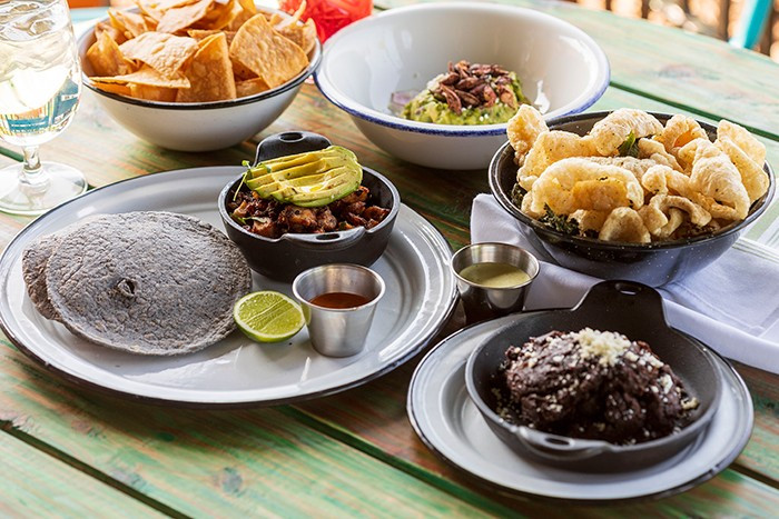 An overhead shot displaying A'Verde's octopus tacos, local NC crispy pork rinds, kale, and Dad's refried beans, tempting viewers with an array of flavorful and visually appealing dishes.